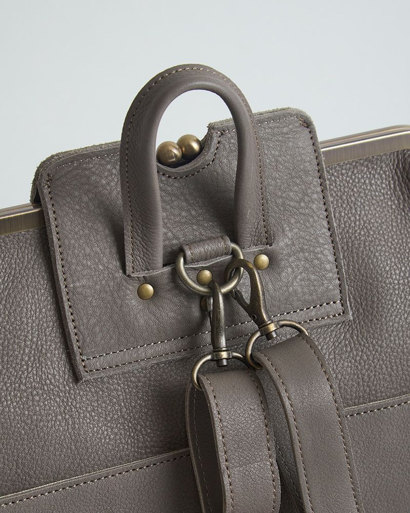 がま口の丸いつまみがちらりと見える絶妙デザインで、遊び心をそっと添える。