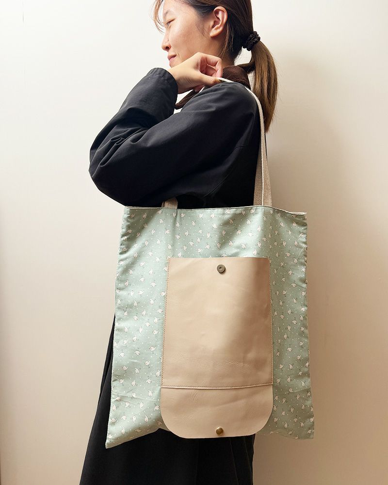 前面に大きくあしらった牛革ポケットは、すべすべと指先に馴染むやわらかさ。（カラー：ことりの散歩）